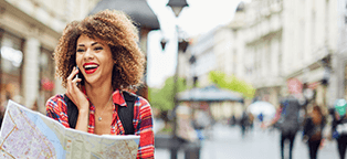 Femail tourist on cell phone smiling with map in hand unaware of surroundings
