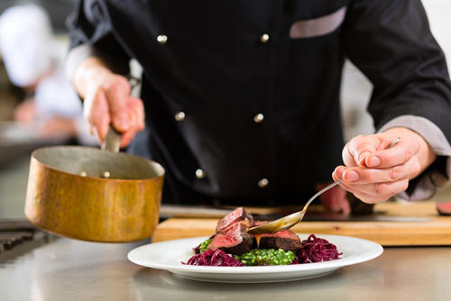 waiter serving sauce over a steak